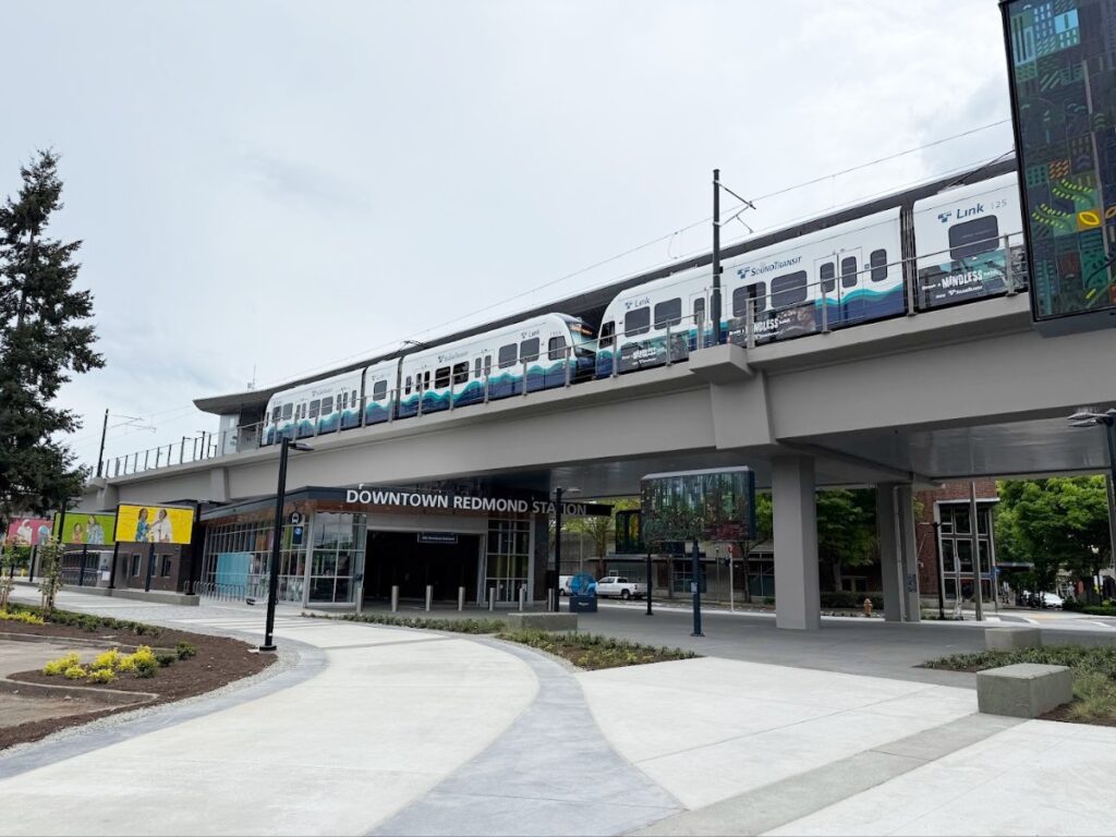 Elevated light rail train passing over the Downtown Redmond Station entrance.