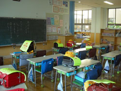 1年2組の教室 (椅子の背にかけてあるのは、防災頭巾)