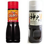 Two soy sauce condiment bottles side by side; left has a red label and cap, right has a white label and cap on a light background.