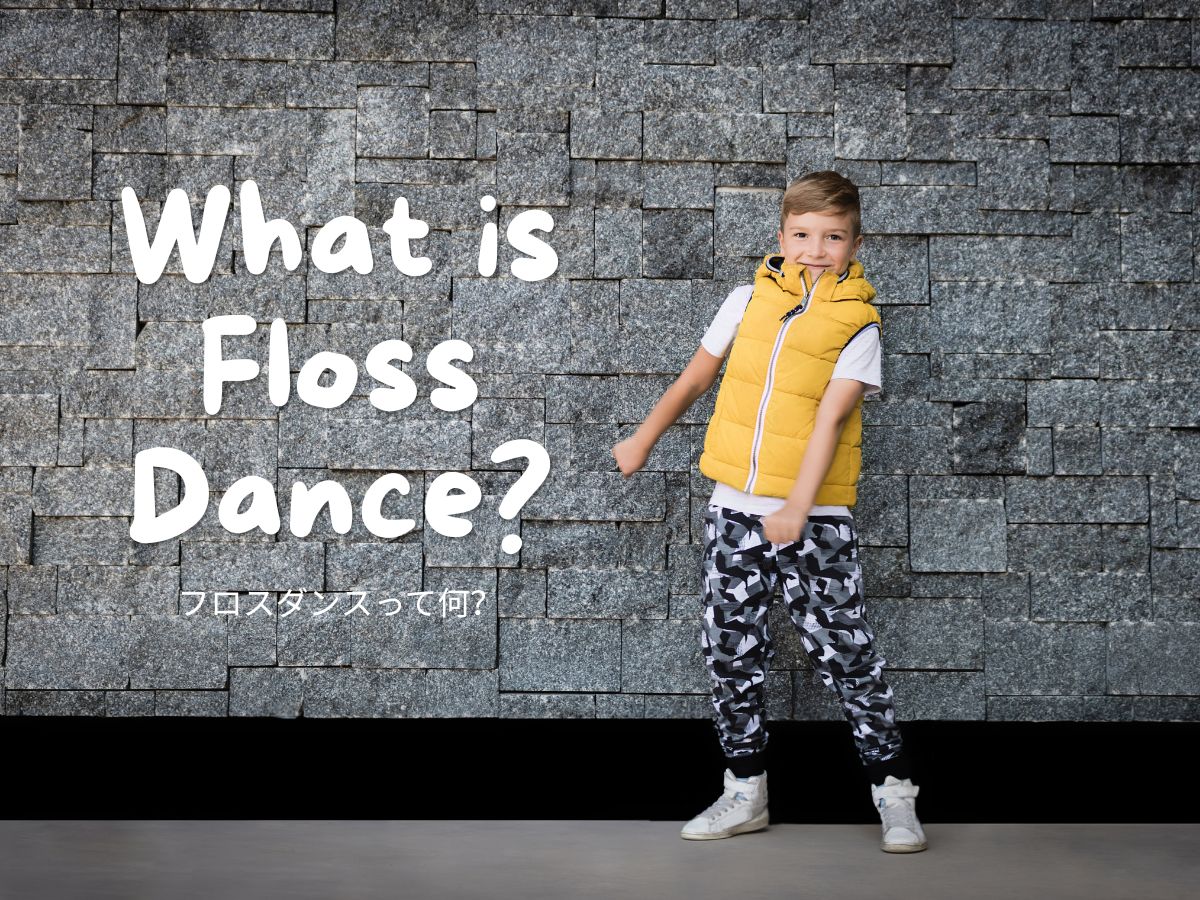 Boy in a yellow puffer vest stands against a gray stone wall with bold white text: 'What is Floss Dance?' and Japanese caption underneath.