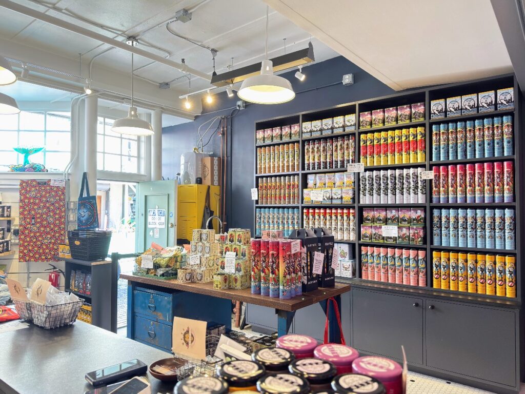 bite-society-1 - junglecity.com Interior of a colorful shop with tall shelves filled with neatly arranged colorful cans and boxes along dark cabinetry.
