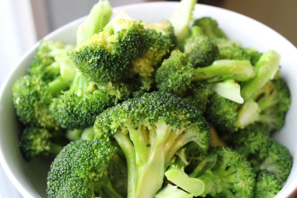 Fresh broccoli florets in a white bowl, close-up.