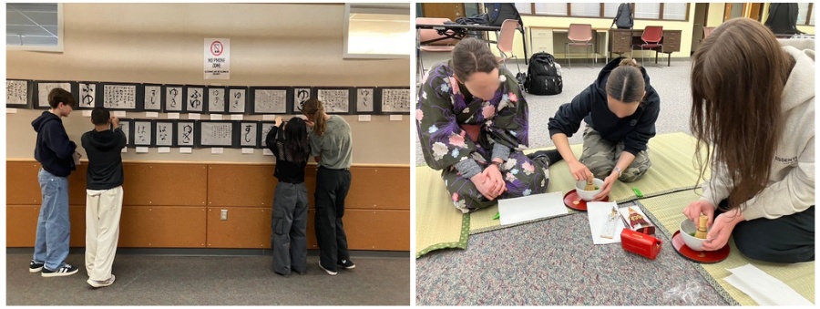 Four students stand along a wall displaying sheets of paper with Japanese characters, examining the calligraphy display in a classroom hallway. (Informative image)