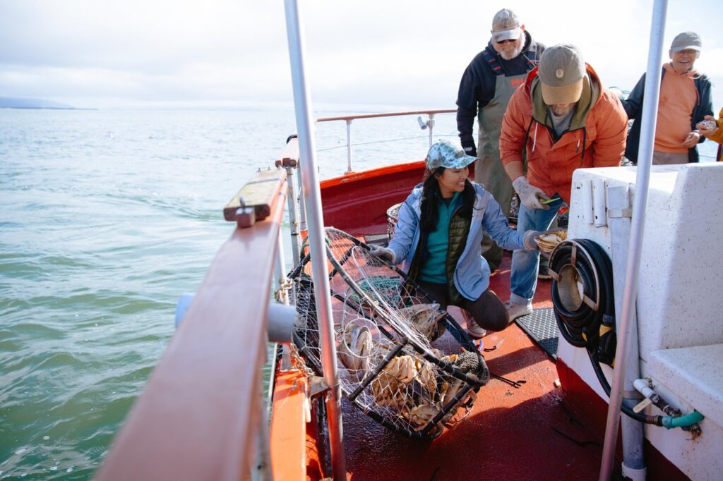 crabbing-3 - junglecity.com Crew on a red fishing boat haul a lobster trap full of shells from the water