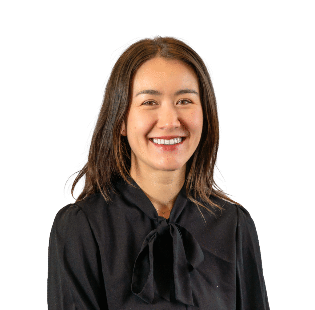Smiling woman with shoulder-length brown hair wearing a black blouse with a bow tie
