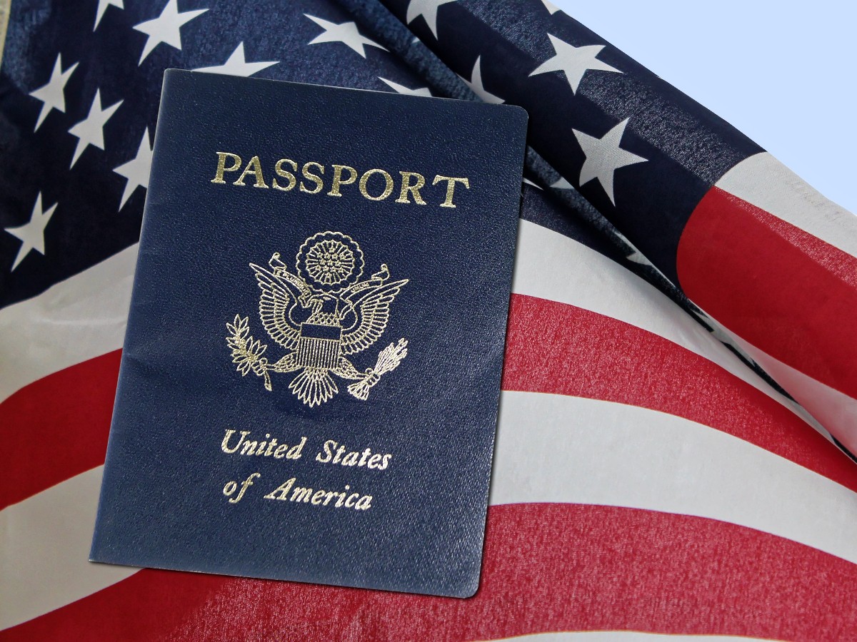 Blue US passport resting on a waving American flag background, with gold embossed text and seal visible