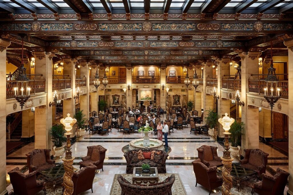 davenport-hotel-1 - junglecity.com Luxurious hotel lobby with a marble floor, central fountain, and upholstered seating around a grand atrium.