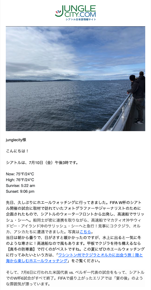 Two people stand at the railing of a boat, looking out over a vast ocean under a blue, partly cloudy sky.