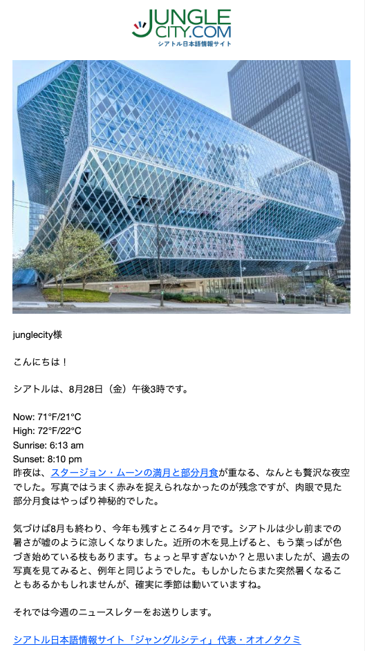 Futuristic glass building with a diamond-patterned facade against a blue sky, with trees and a street in the foreground.
