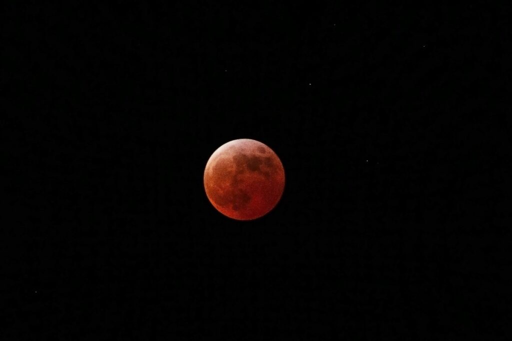 Blood-red Moon during a total lunar eclipse against a dark night sky.