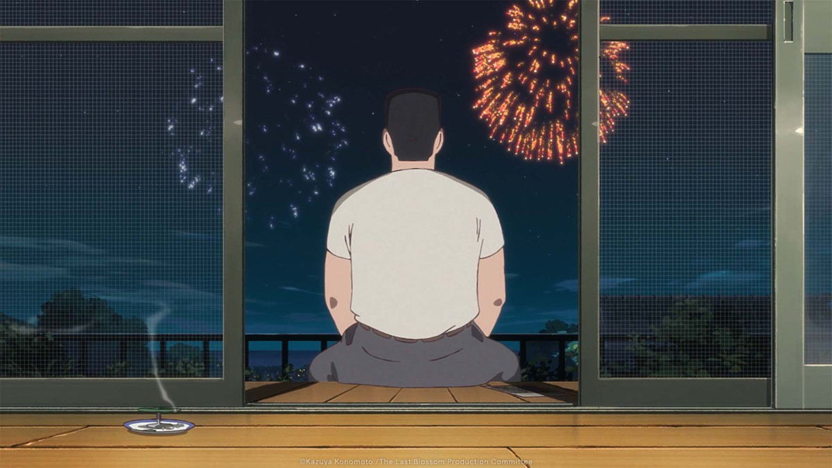 Man sits with his back to the viewer on a balcony at night, watching fireworks in the sky.
