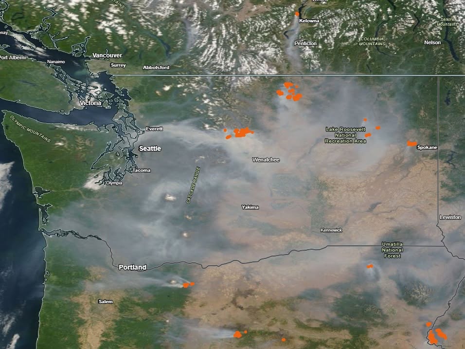 Satellite map showing wildfire smoke plumes and orange fire hotspots across Washington and Oregon, including Lake Roosevelt Recreation Area and Portland area