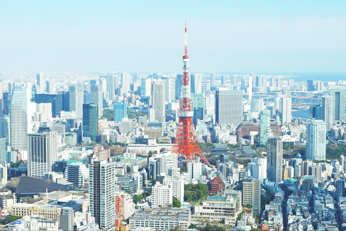 Aerial view of central Tokyo with Tokyo Tower rising among skyscrapers.