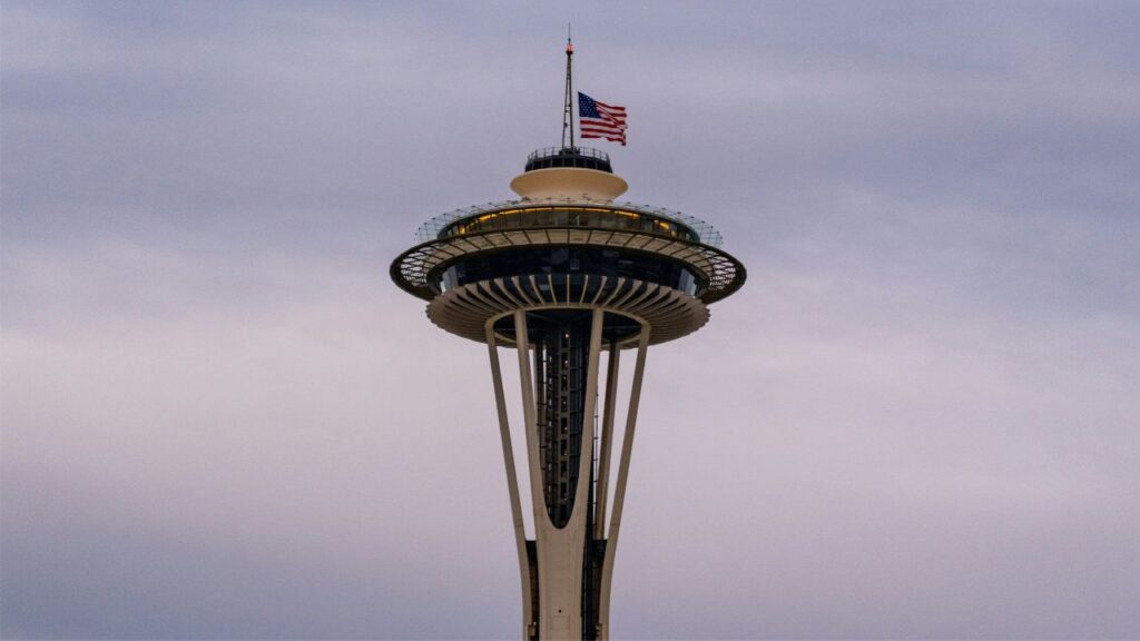 Seattle Space Needle with the American flag on top against a pale sky