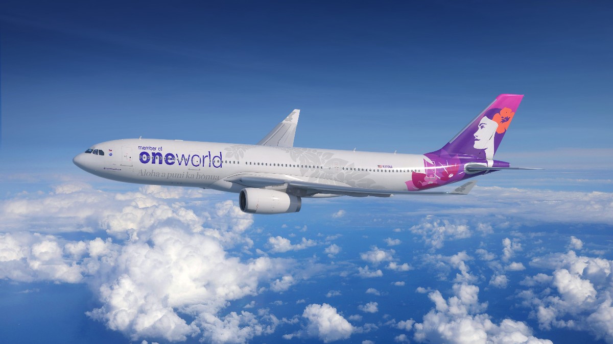 Airliner in flight above clouds with OneWorld branding on the fuselage and a purple tail design.