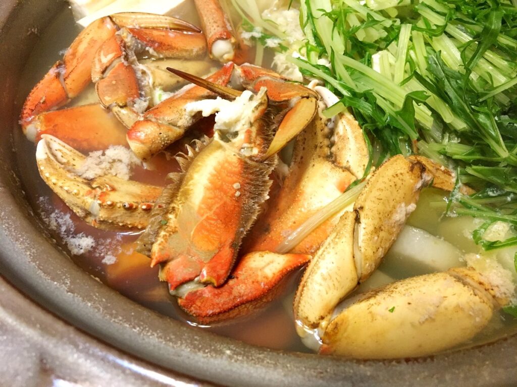 crab-hot-pot-1 - junglecity.com Lobster claws and shell pieces simmering in a light broth with chopped green onions nearby in a pot.