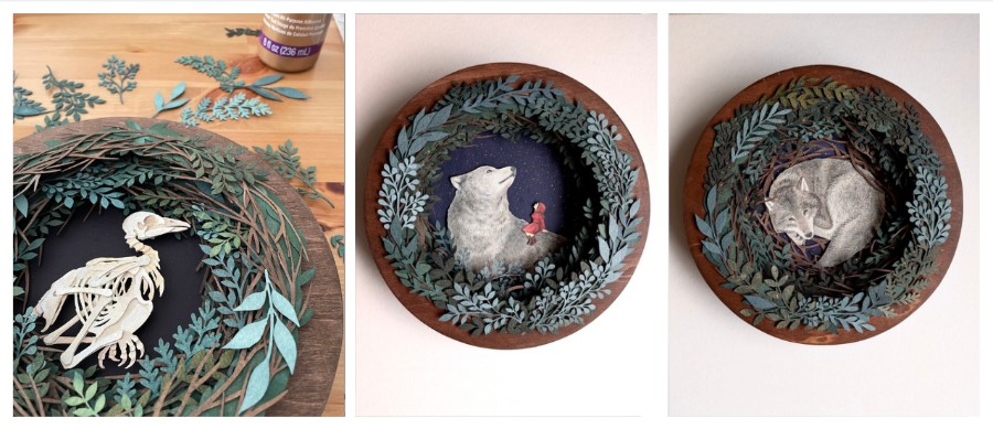Round wooden frame with a white animal skeleton inside a teal leaf wreath on a dark background.